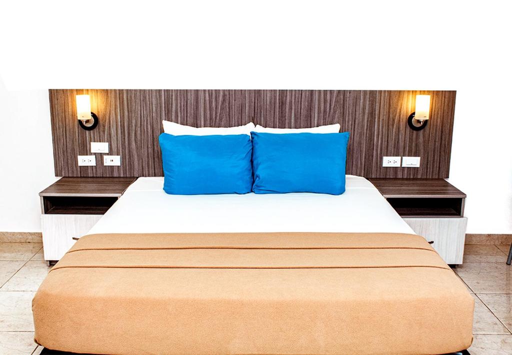 a bedroom with a large bed with blue pillows at Hotel Kariña Guanipa in San José de Guanipa