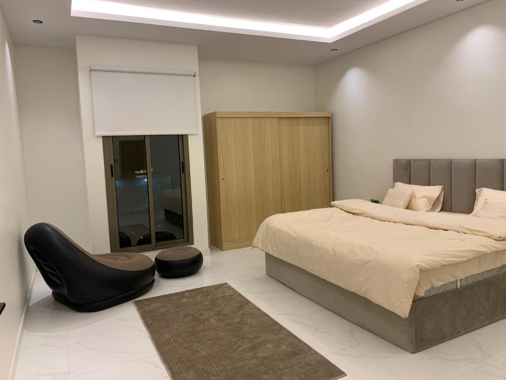 a bedroom with a bed and a black chair at شقة فاخرة in Al Kharj