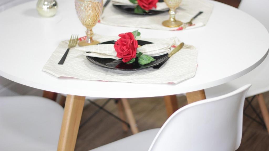 uma mesa com dois pratos e uma rosa vermelha em Chalés Florescer nos Canyons em Praia Grande