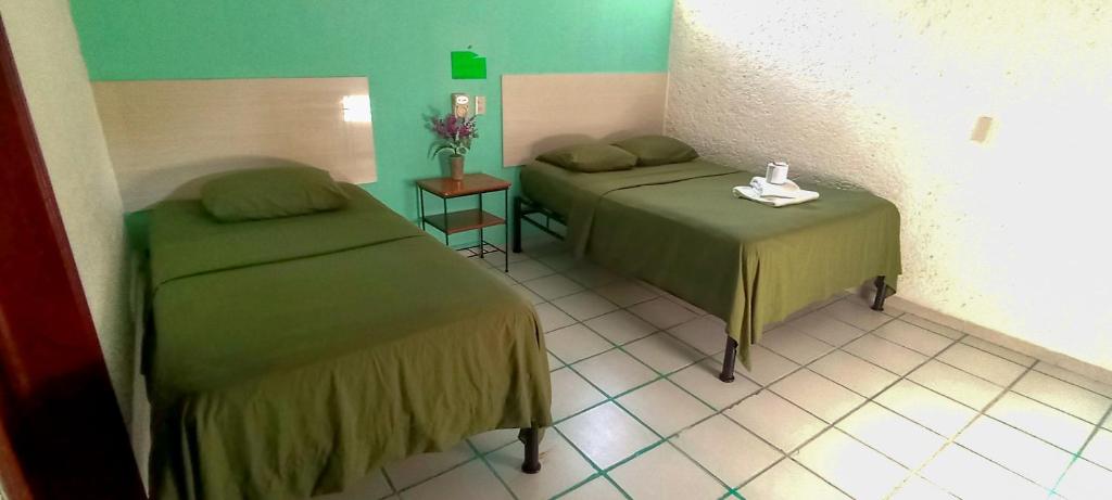 a room with two beds and a table with flowers at Posada Nacha`n - Ka`an in Palenque