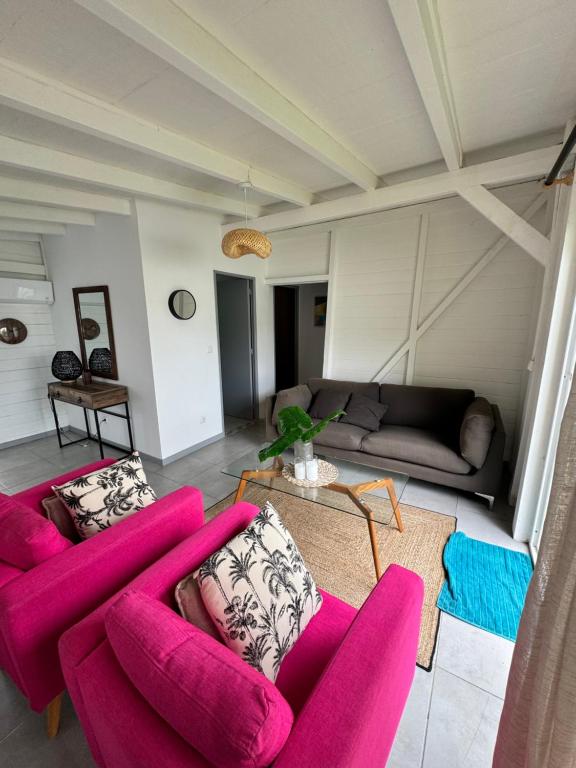 un soggiorno con 2 sedie rosa e un divano di Villa citron a Ducos