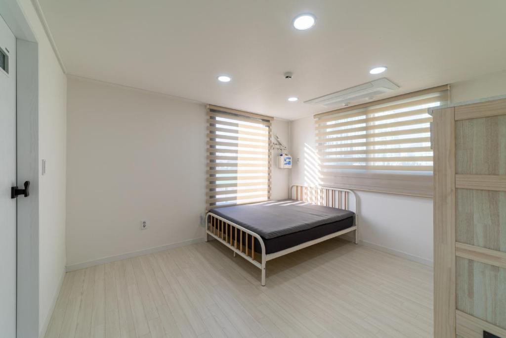 ein Schlafzimmer mit einem Bett in einem Zimmer mit Fenstern in der Unterkunft The house has 4 bedrooms and 3 bathrooms. in Busan