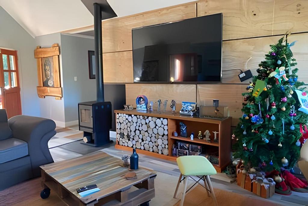 uma sala de estar com uma árvore de Natal e uma televisão em Casa Rural con opción de tina temperada em Puerto Varas