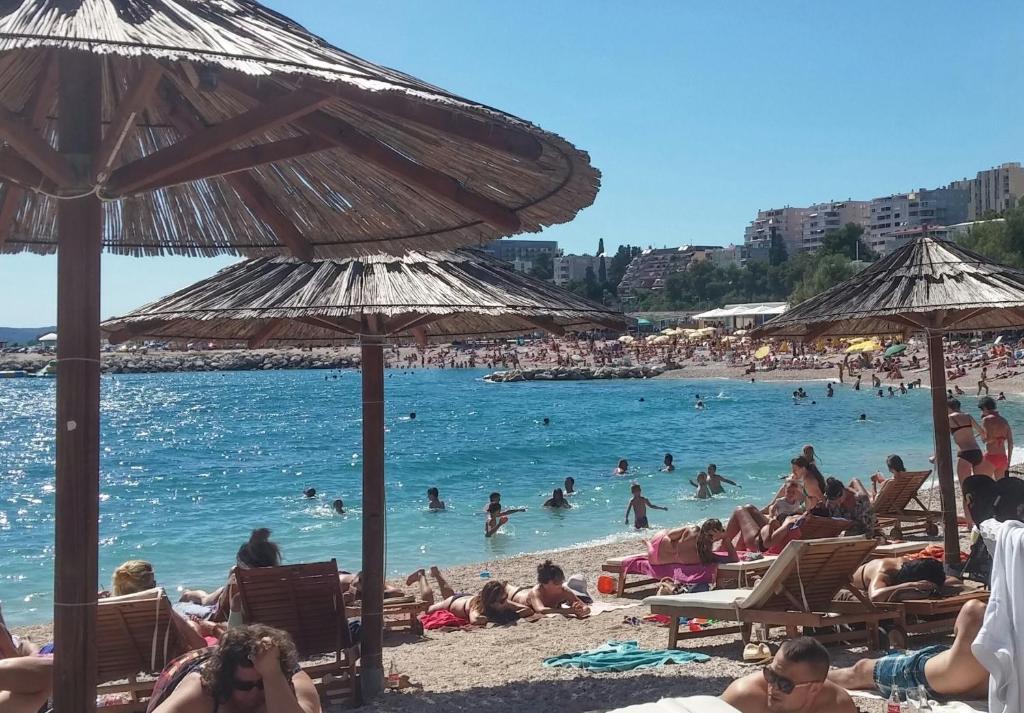un groupe de personnes sur une plage avec parasols dans l'établissement Apartment Josip Split, à Split