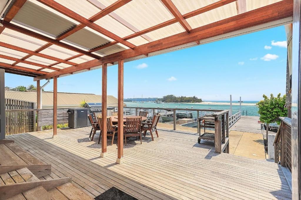 a deck with a table and chairs and the ocean at Boatshed in Huskisson