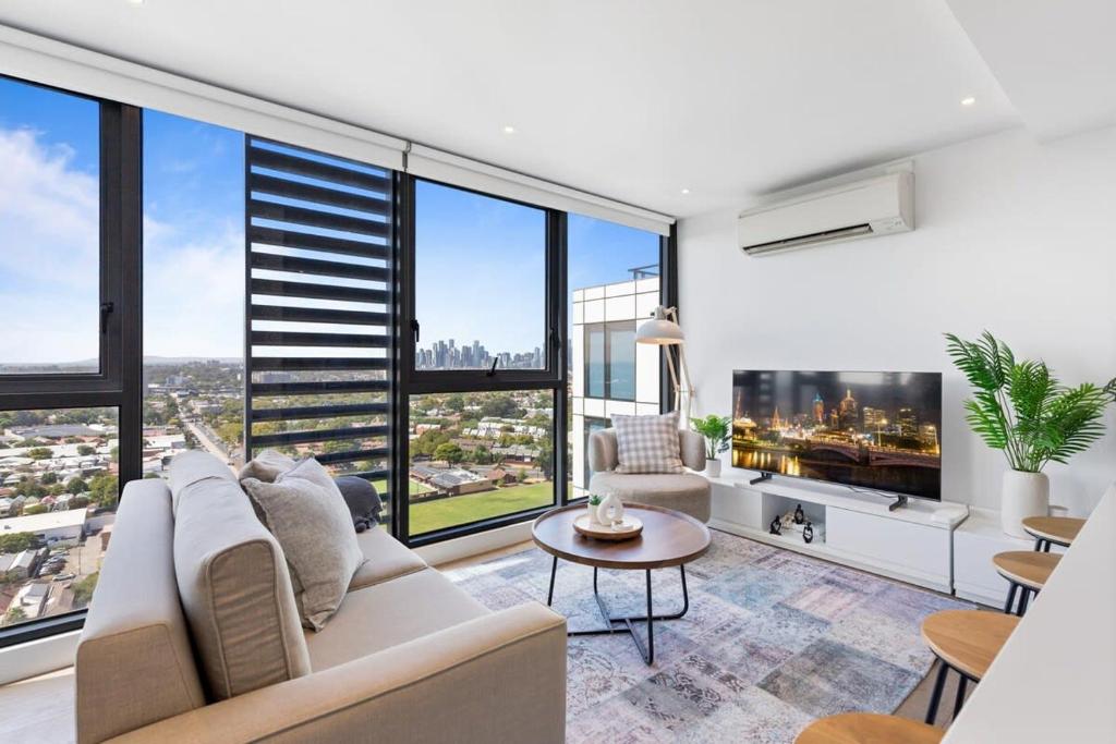 uma sala de estar com um sofá e janelas grandes em Elegant Inner-West 2-Bed with City Views & Pool em Melbourne