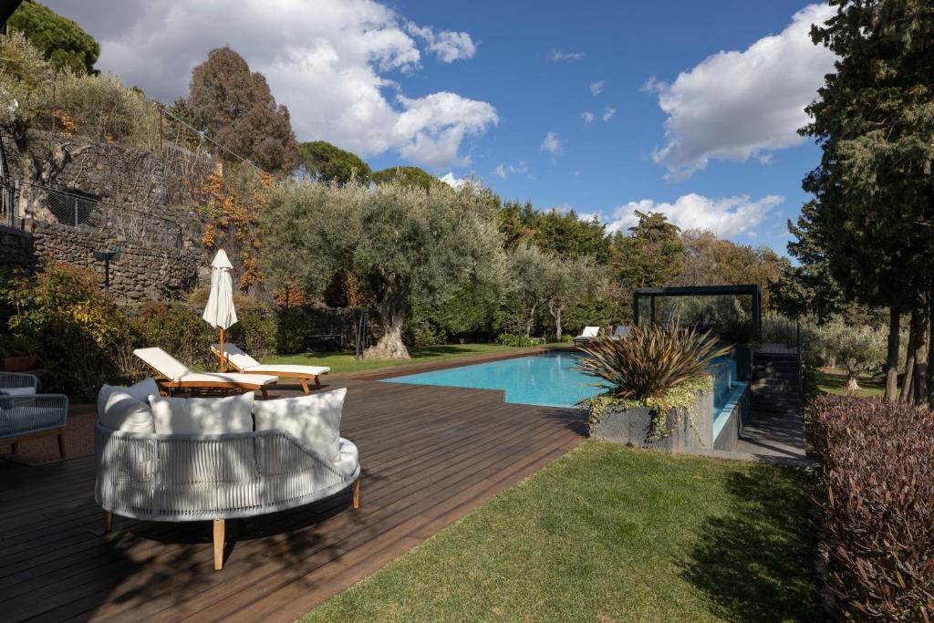 un patio trasero con piscina y terraza de madera en Lussuosa Villa di Design in Sicilia con Piscina e Vista Mare Relax e Comfort a 5 stelle, en Ragalna