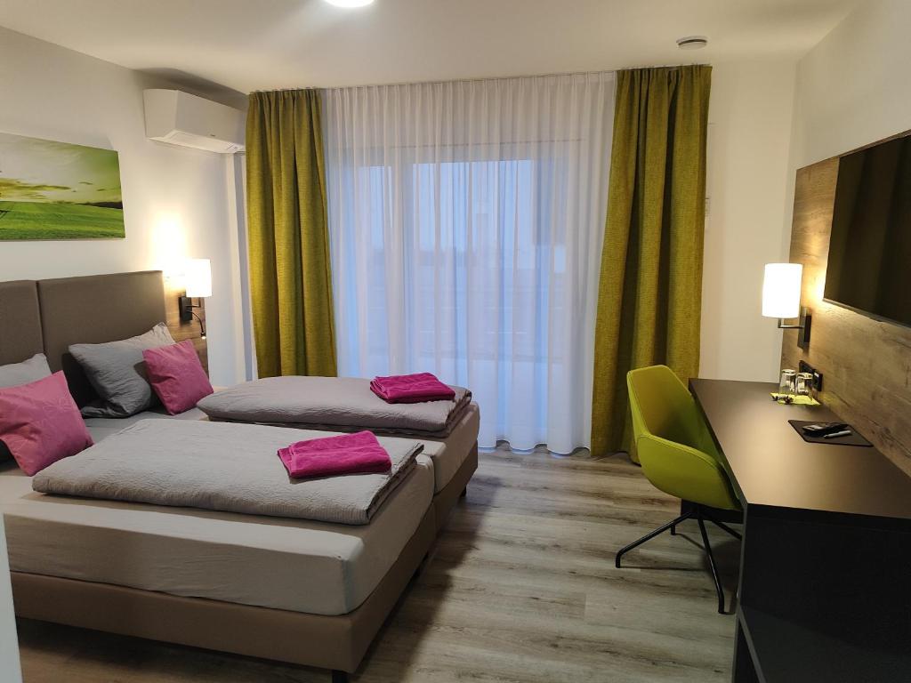 ein Hotelzimmer mit 2 Betten und einem Schreibtisch in der Unterkunft Hotel Gästehaus Stock Zimmer Bäumle in Friedrichshafen