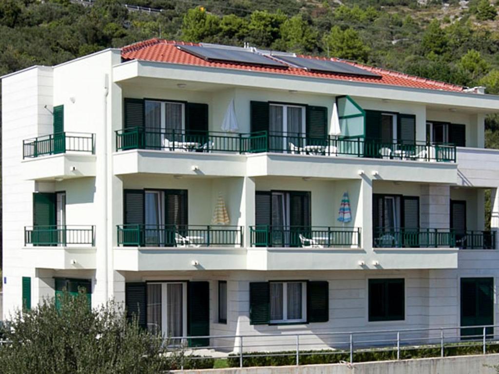 un edificio bianco con balconi in cima di Apartments by the sea Igrane, Makarska - 17292 a Igrane