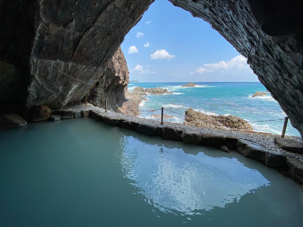 a cave with a pool of water in front of the ocean at Hotel Urashima in Katsuura