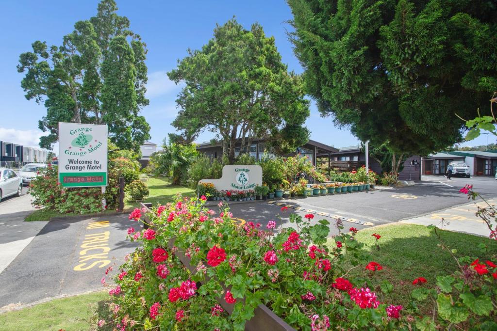 un jardin avec des fleurs et un panneau devant un bâtiment dans l'établissement Grange Motel, à Auckland