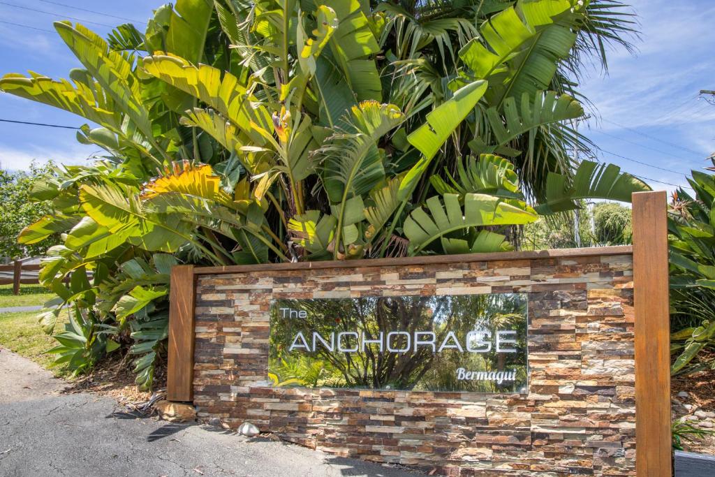 a sign on a brick wall with plants at The Anchorage Bermagui in Bermagui