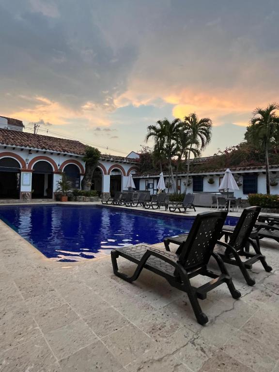 uma piscina com duas espreguiçadeiras em frente a um edifício em Hotel Villa María Santa Fe de Antioquia em Santa Fe de Antioquia