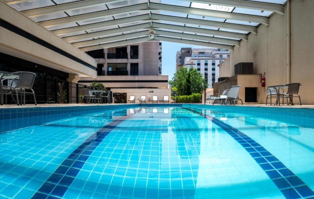 a large swimming pool with blue tiles in a building at Flat de Luxo Aeroporto Congonhas - Hotel in Sao Paulo