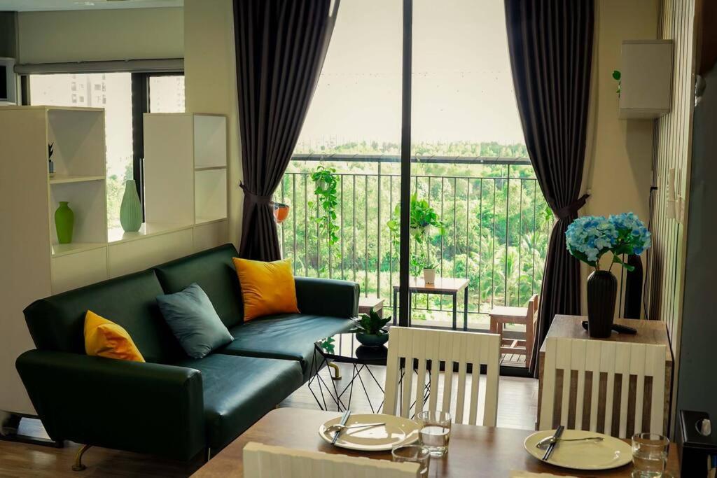 a living room with a green couch and a large window at The Origami: Exclusive Living ! in Long Bình