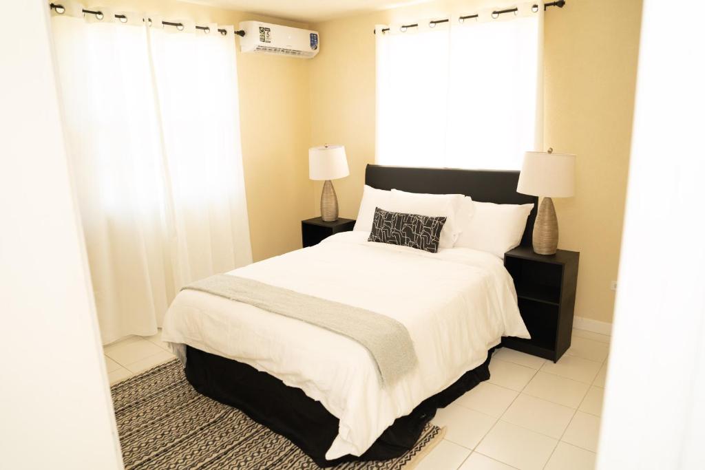 基督堂區的住宿－Sunset Cove Barbados，一间卧室设有一张床和两个窗户。