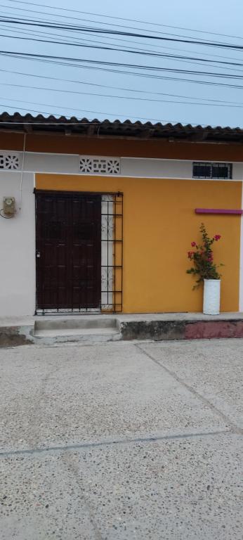 een geel-wit huis met een zwarte deur bij Casa Katiuska in Mompos