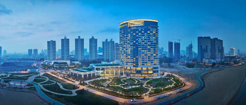 a tall building in the middle of a city at Shangri-La Qinhuangdao in Qinhuangdao