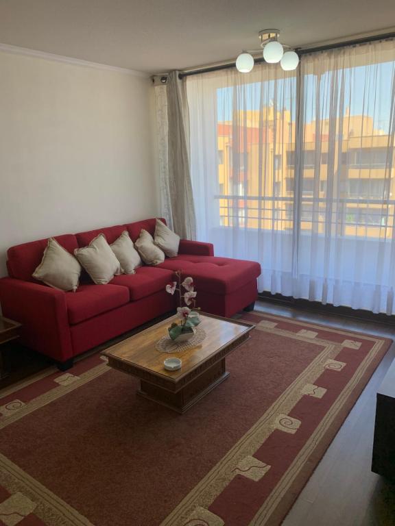 uma sala de estar com um sofá vermelho e uma mesa de centro em Departamento LA FLORIDA em Santiago