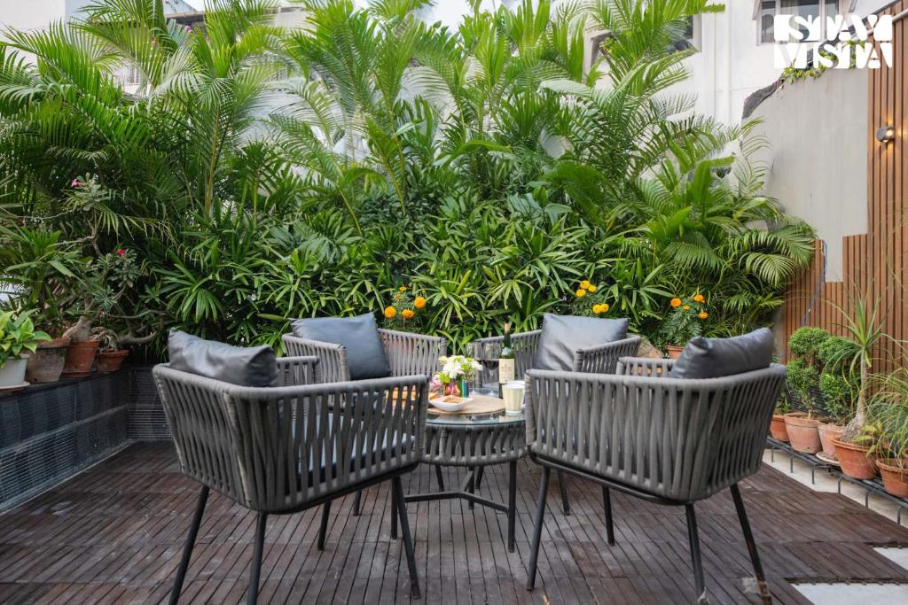 un patio con sillas, mesa y plantas en StayVista's Vogue Vista - Contemporary Chic Interiors, Terrace & Indoor-Outdoor Games, en Calcuta