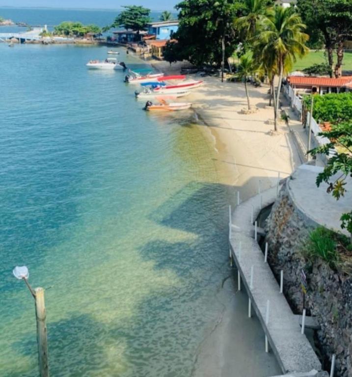 a group of boats in the water next to a beach at Suíte do Betão in Mangaratiba