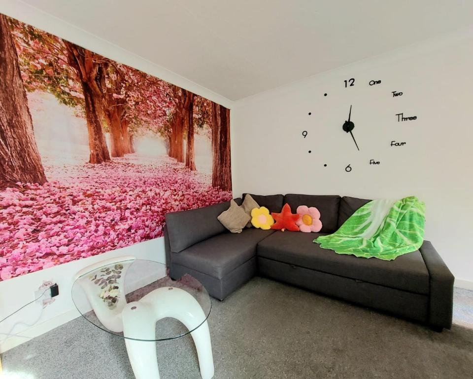 a living room with a couch and a clock on the wall at The Blossom - Largs in Largs