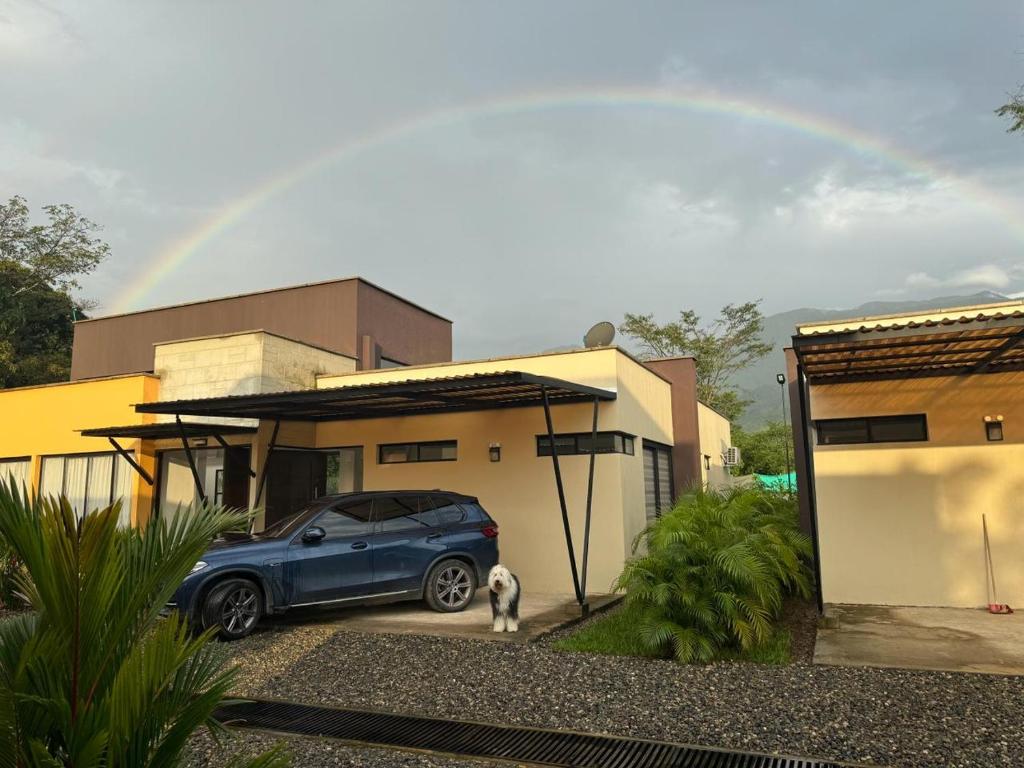ein blaues Auto, das vor einem Haus mit Regenbogen parkt in der Unterkunft Casas Campestres El Secreto in Restrepo