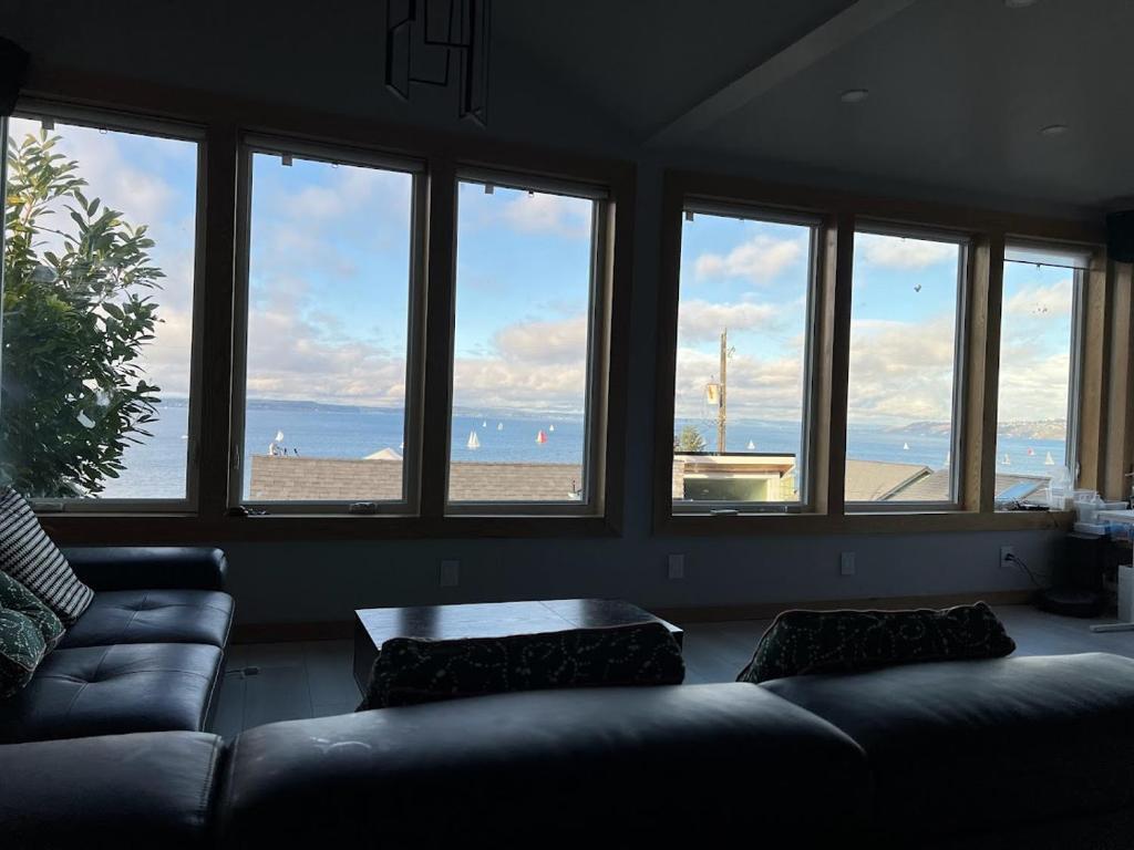 een woonkamer met een bank en uitzicht op het strand bij Pacific View Home in Seattle