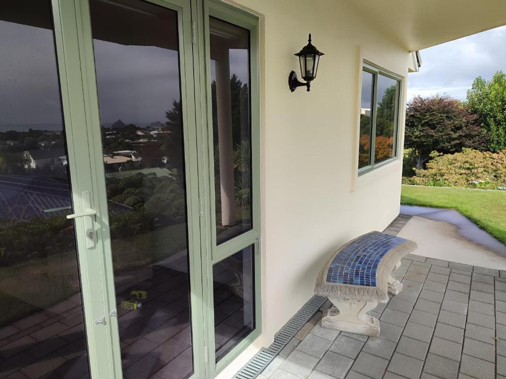 a porch with a bench next to a glass door at Home with sea views in New Plymouth