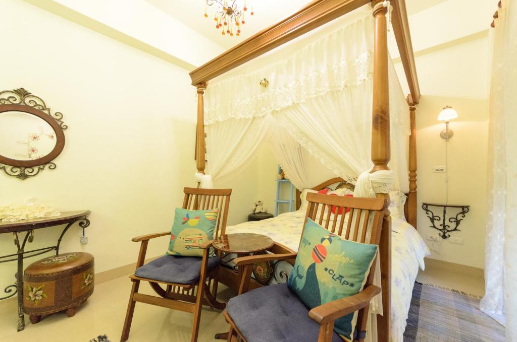 a bedroom with a canopy bed and two chairs at 晶藍色美人魚 Mermaid Inn in Hualien City