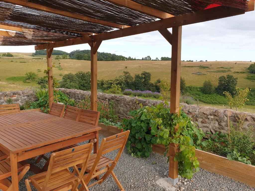 a wooden table and chairs under a wooden pergola at Maison l&#39;âne vert in Lay