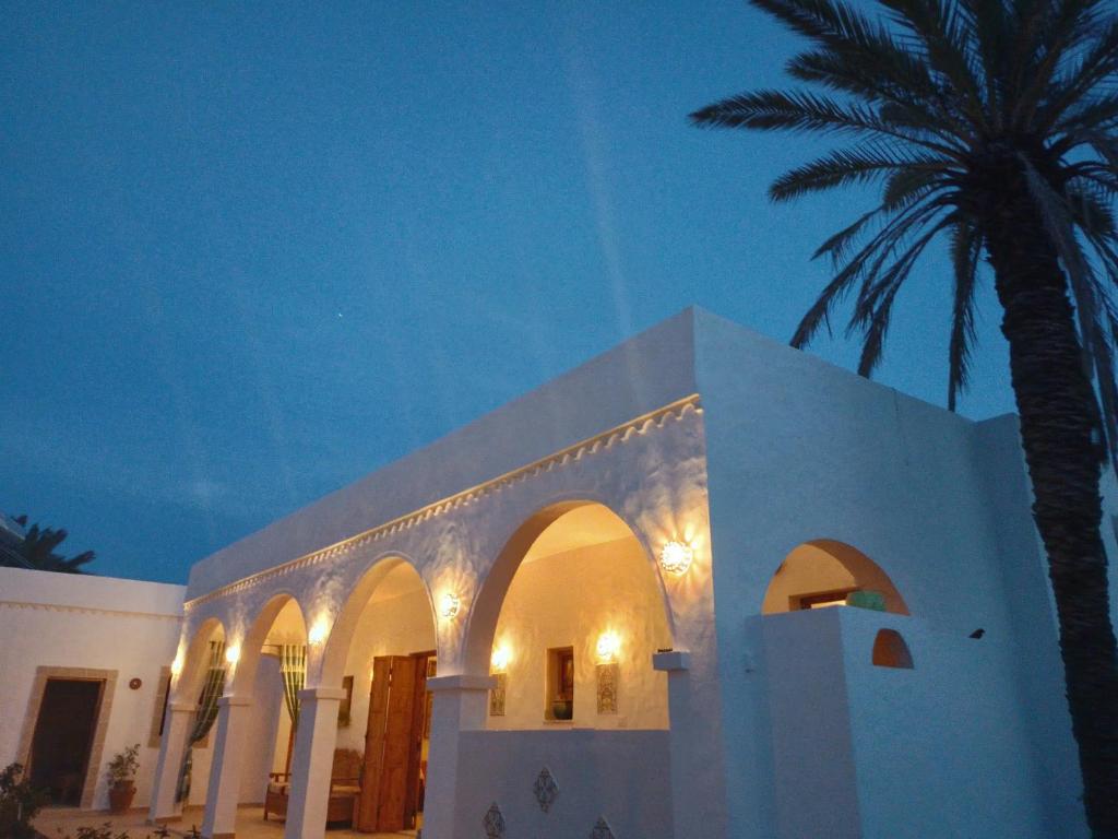 um edifício branco com uma palmeira ao lado em Djerba rêve vacances Zohra em Midoun