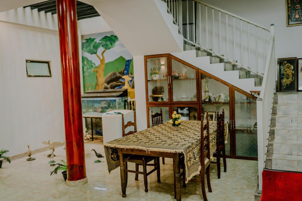 ein Esszimmer mit einem Tisch, Stühlen und einer Treppe in der Unterkunft Lihini Villa ii in Matara