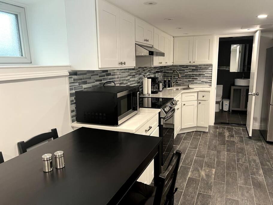 WoodhavenにあるModern & cozy basement apartment near JFK airportのキッチン(白いキャビネット、黒いカウンタートップ付)