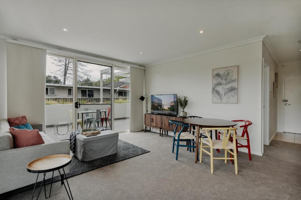 uma sala de estar com um sofá, uma mesa e cadeiras em Peaceful 1-Bed Apartment Close to Lonsdale St em Camberra