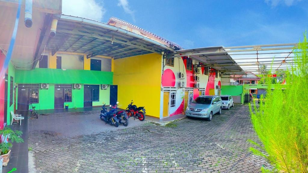 a colorful building with motorcycles parked in a parking lot at Angel Home Stay by Nusalink in Warungsergon