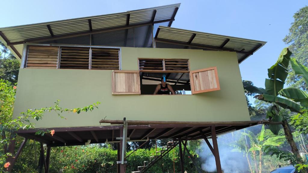 a woman looking out of a window of a house at Villalu. in Cahuita