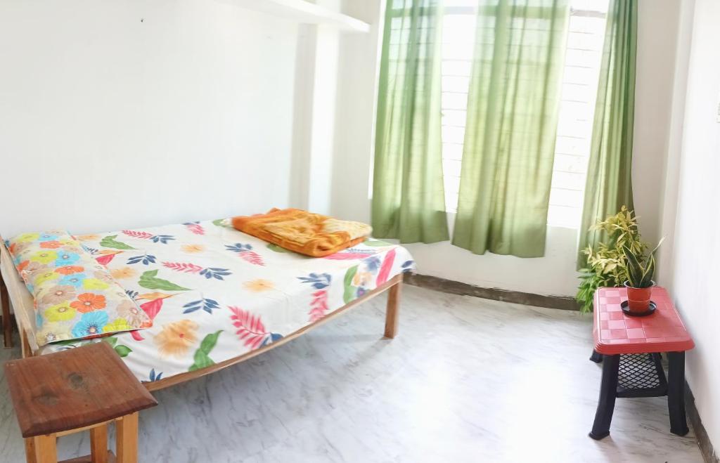 Cama en habitación con cortinas verdes en Serendipia en Dimāpur