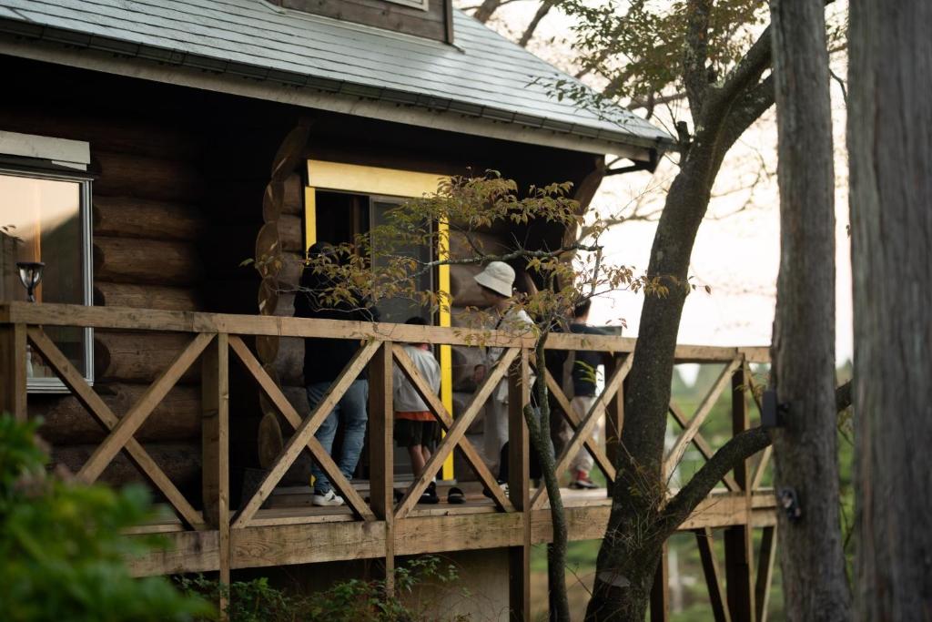 un hombre parado en el porche de una cabaña de madera en Renesto aHOLIDAYHOME - Vacation STAY 28000v en Kobe