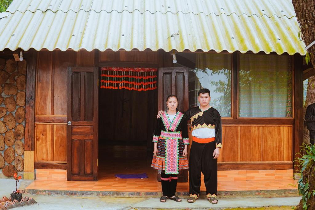 a man and a woman standing in front of a house at A Dế Homestay Sơn Tra in Phong Thổ