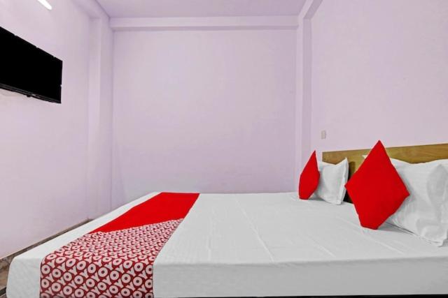 a bedroom with a bed with red and white pillows at The Krishna Stays in Mathura