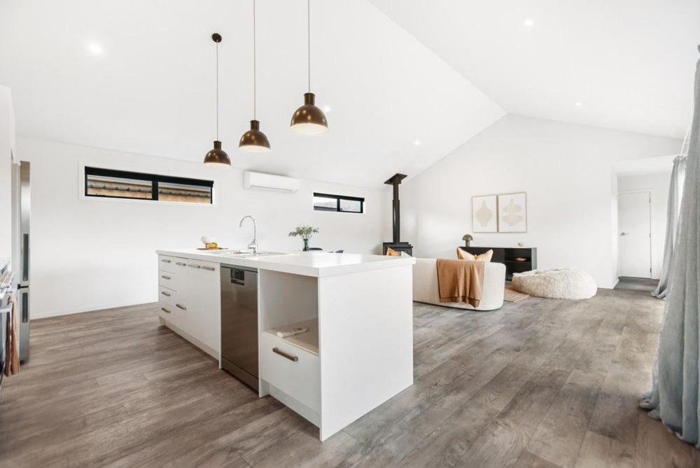 a white kitchen with a sink and a living room at Magic Central Wanaka Living in Wanaka