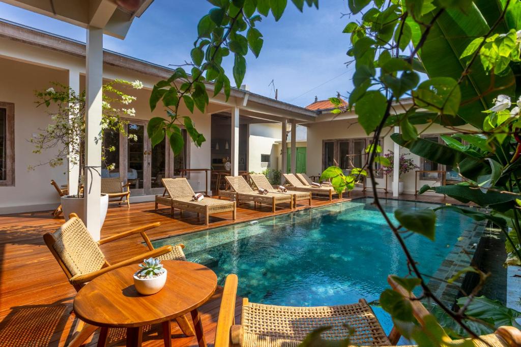 a swimming pool with chairs and a table and a house at RIYURI GUESTHOUSE in Tumbak Bayuh
