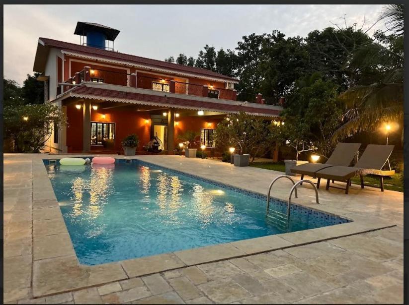 a house with a swimming pool in front of a house at The Chapters Villa in Alibag