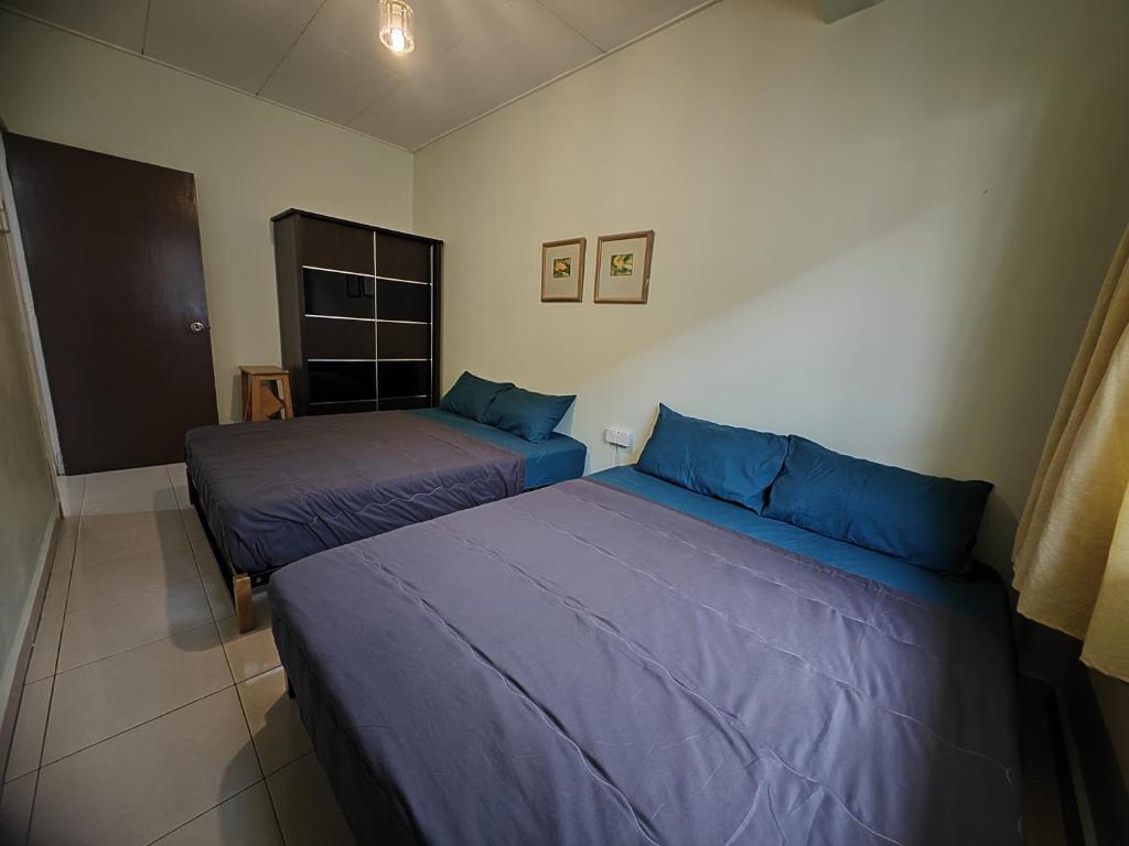 twee bedden in een kamer met blauwe lakens bij Langkawi Perdana Families Suite @ Langkawi Airport in Pantai Cenang