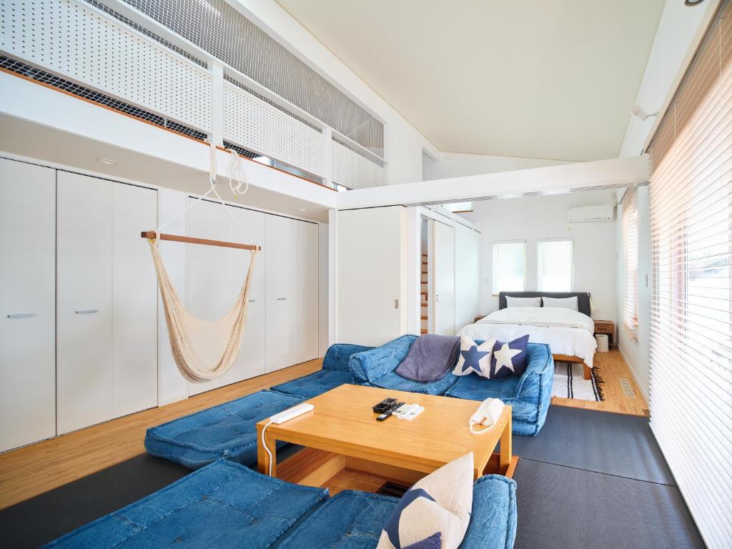 sala de estar con sofá azul y cama en Surf&Turf Aoshima - サーフ&ターフ青島 -, en Miyazaki