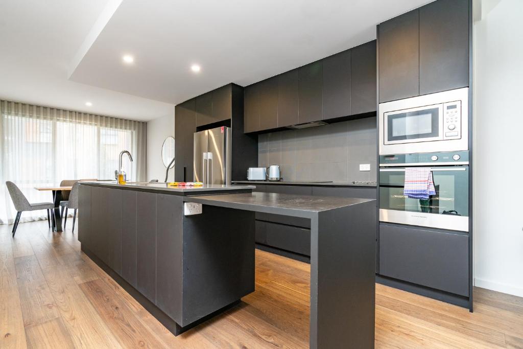 a kitchen with black cabinets and a kitchen island at Contemporary Tri-Level APT in a Prime Central Spot in Canberra