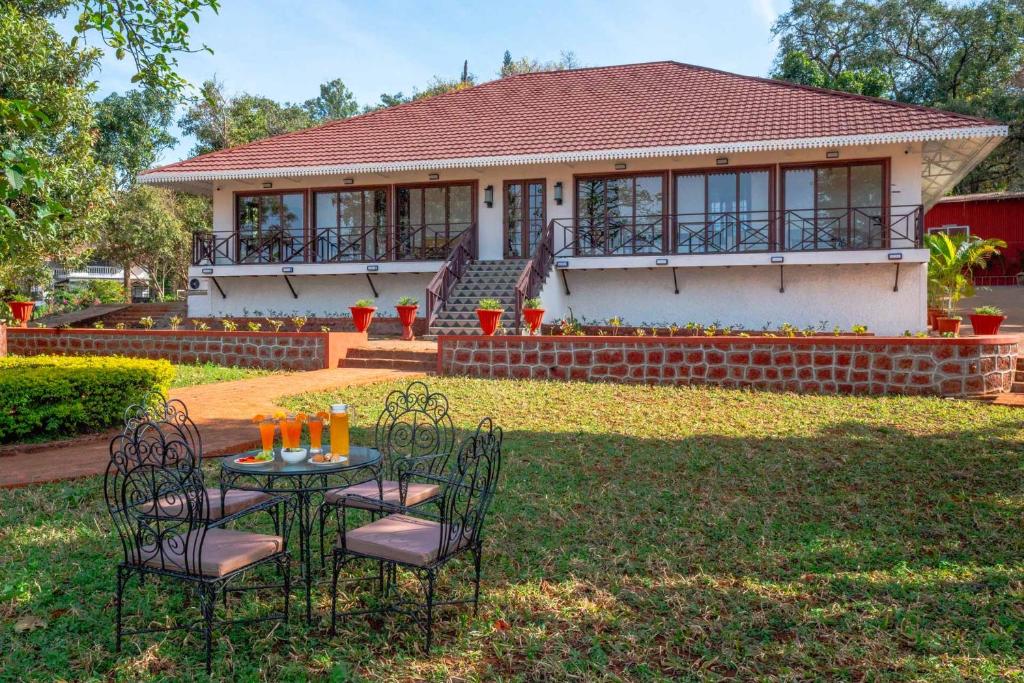 a table and chairs in front of a house at StayVista's Villa Terra - Valley & Lake-View Villa with Spacious Lawn & Indoor Activities in Panchgani