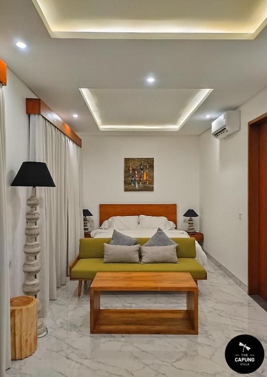 a living room with a green couch and a bed at Capung Smart Residence in Sanur