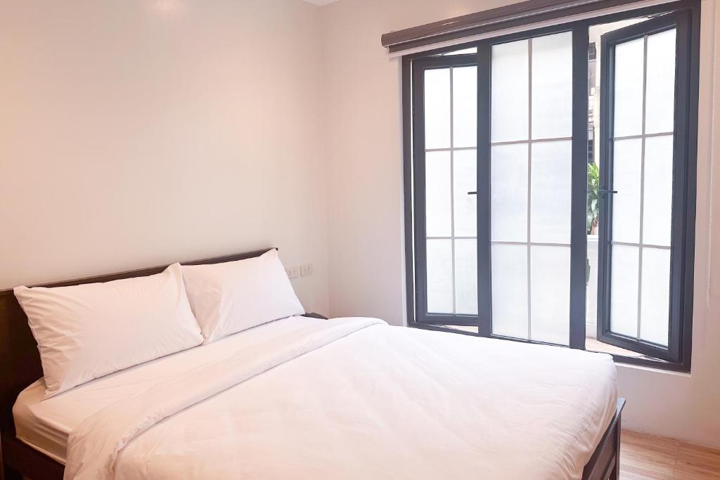 a white bed in a room with two windows at SANTOS Pension House in Manila
